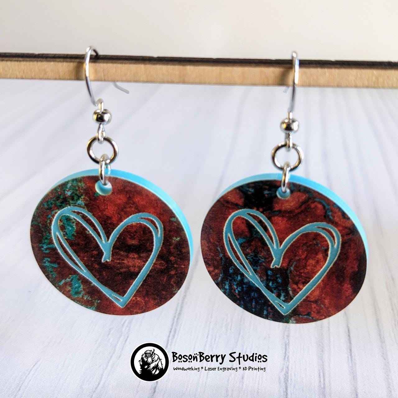 Copper on Turquoise Patterned Acrylic Earrings: round with engraved heart, suspended over white background