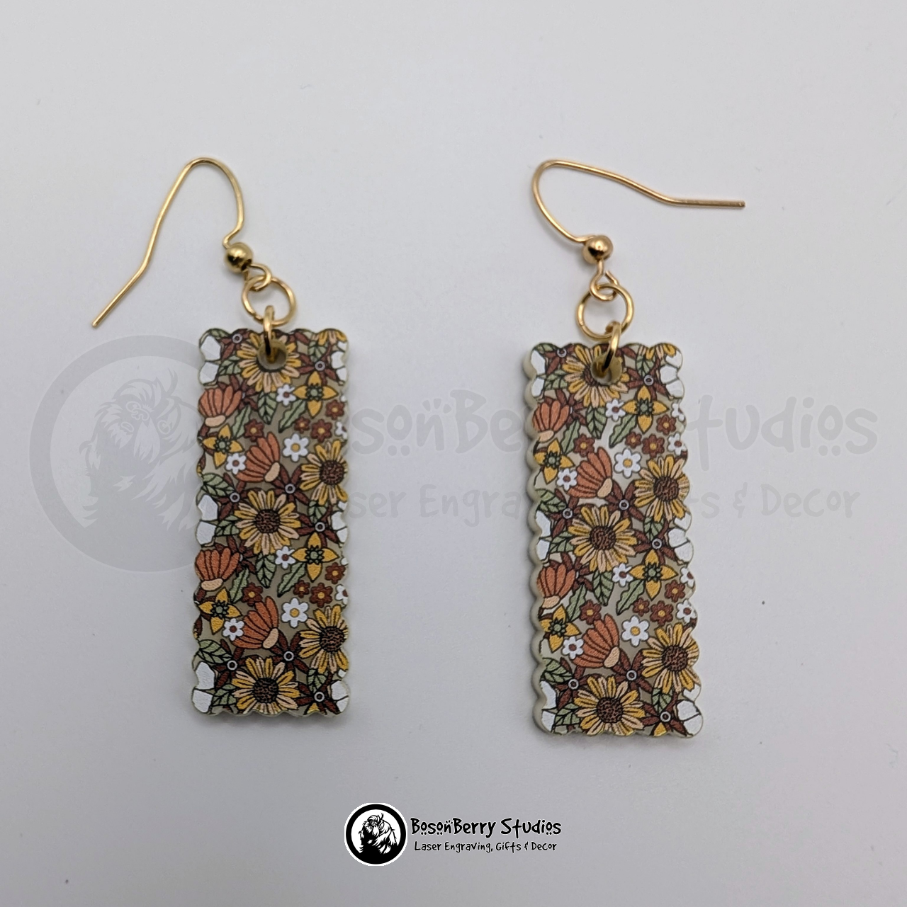 Scalloped rectangle shaped 70s Retro Floral pattern acrylic earrings, with colors yellow, brown, orange and green, on a white background with 'BosonBerry Studios' branding.
