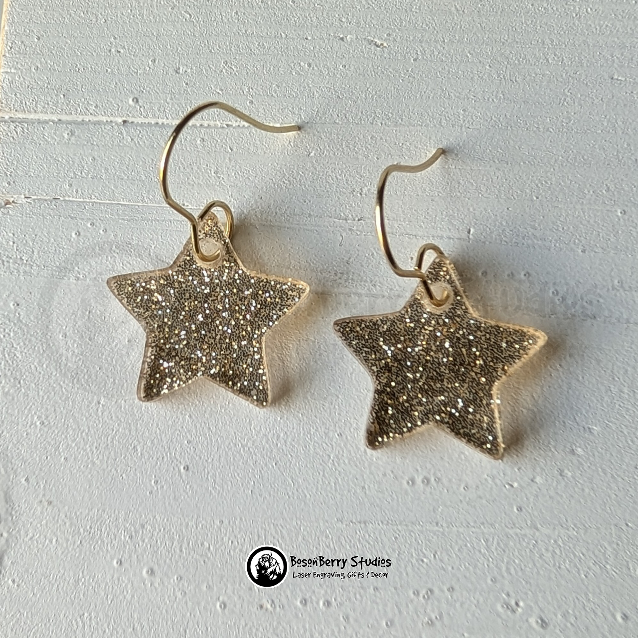 Star-shaped gold glitter earrings on a white background, branded 'BosonBerry Studios'.