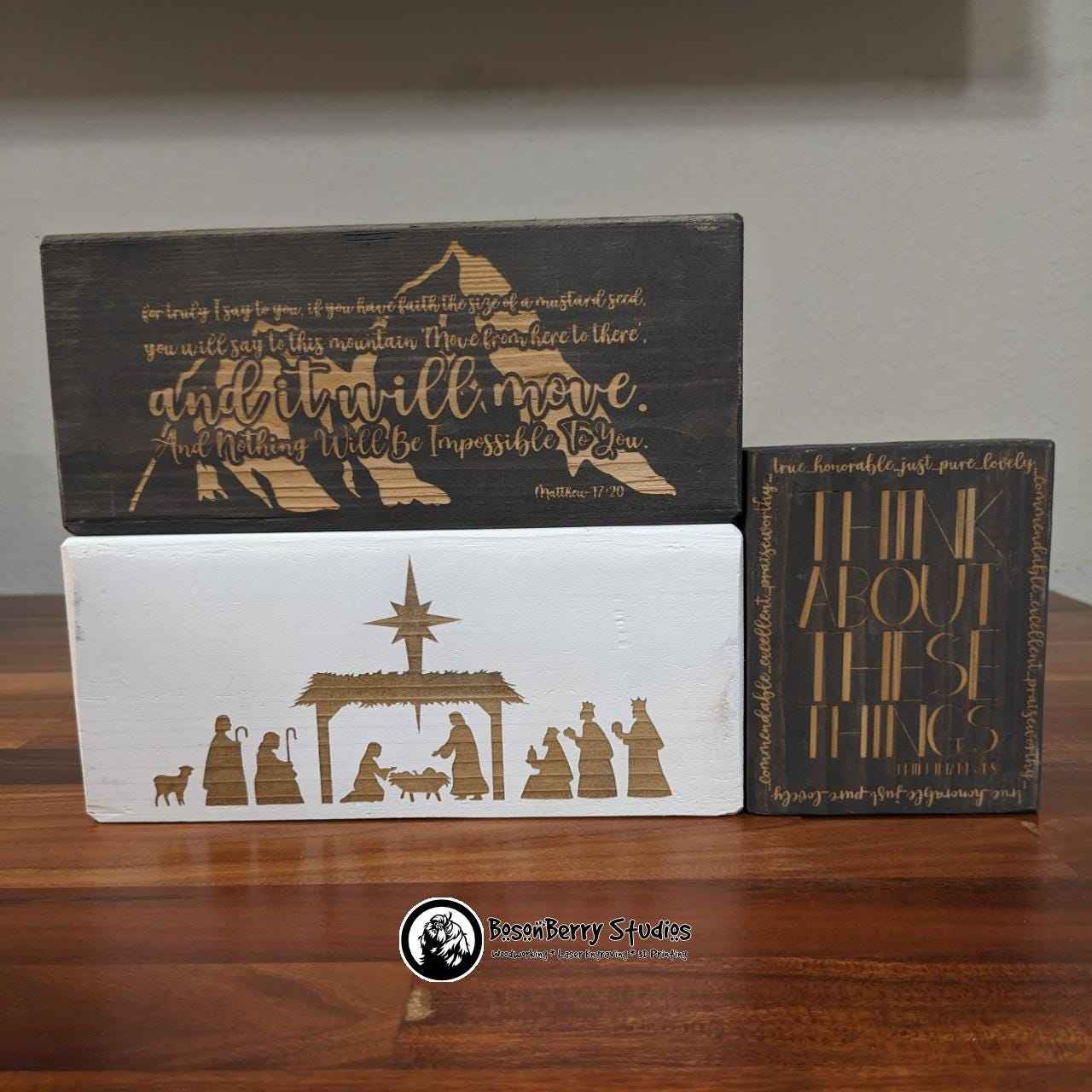 Bible Blocks-Decorative Wooden Shelf Signs - 3 blocks displayed on a wooden counter, a long grey "Faith Moves Mountains", a long white Nativity, and a short grey "Think About These Things"