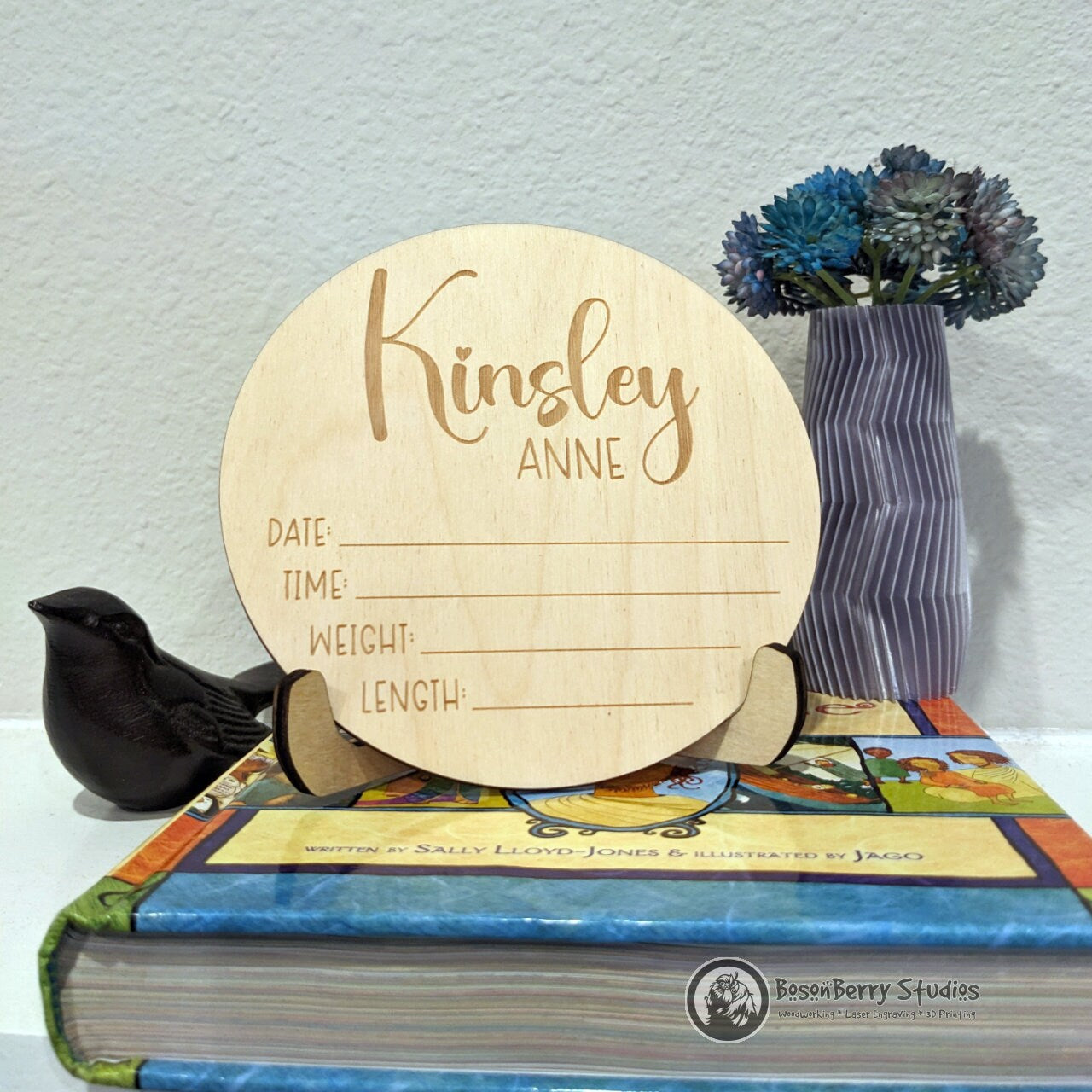 A sign for newborn stats with standing atop a kid's book with décor in the background