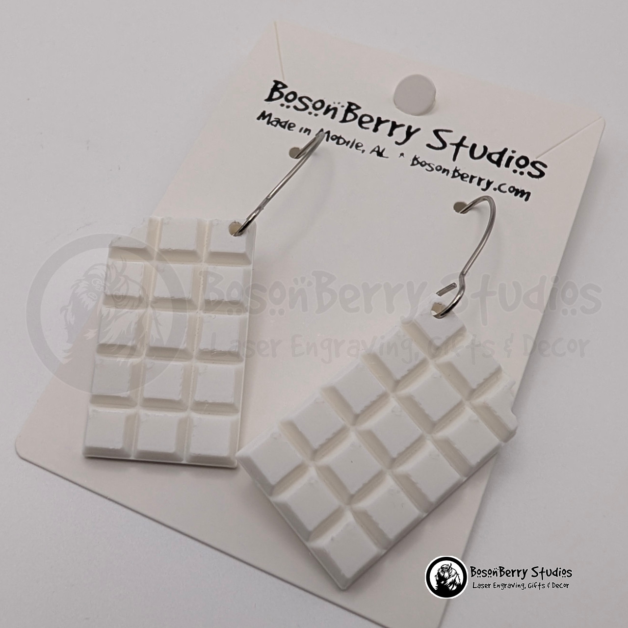 Set of white chocolate bar-shaped earrings on cards with 'BosonBerry Studios' branding.