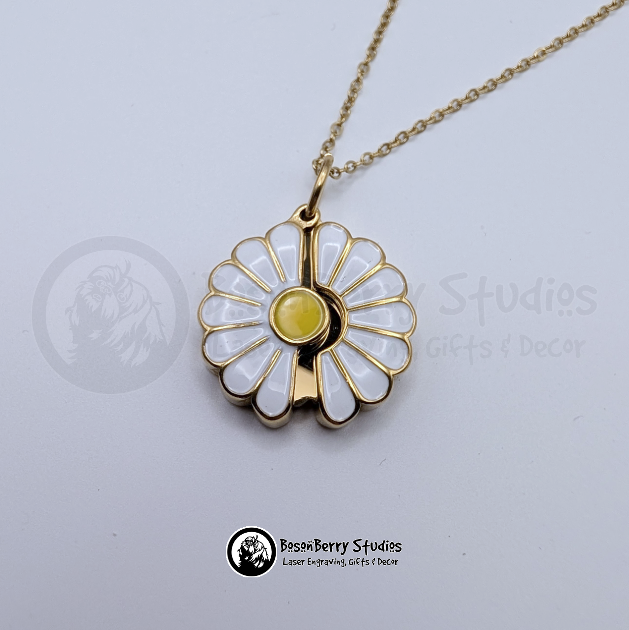 Gold and white enameled daisy pendant on a white background with 'BosonBerry Studios' branding.