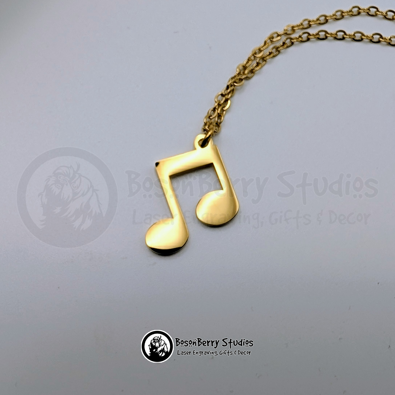 Gold music note pendant necklace on a white background with 'BosonBerry Studios' branding.