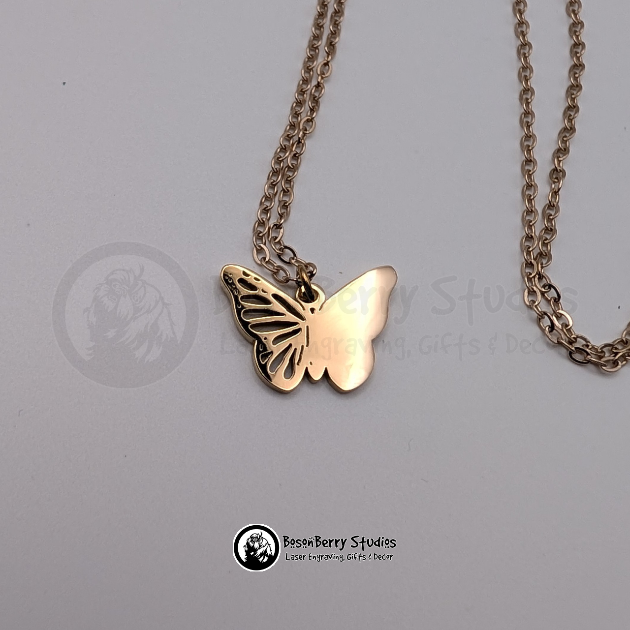 Rose Gold butterfly pendant on a matching chain against a white background with 'BosonBerry Studios' branding.