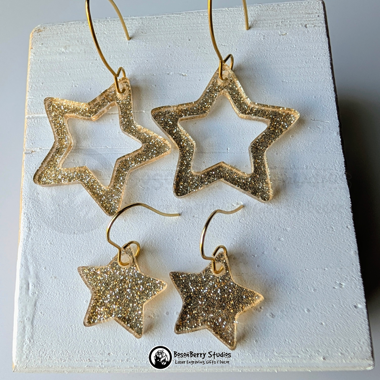 Star-shaped gold glitter earrings on a white background, branded 'BosonBerry Studios'.