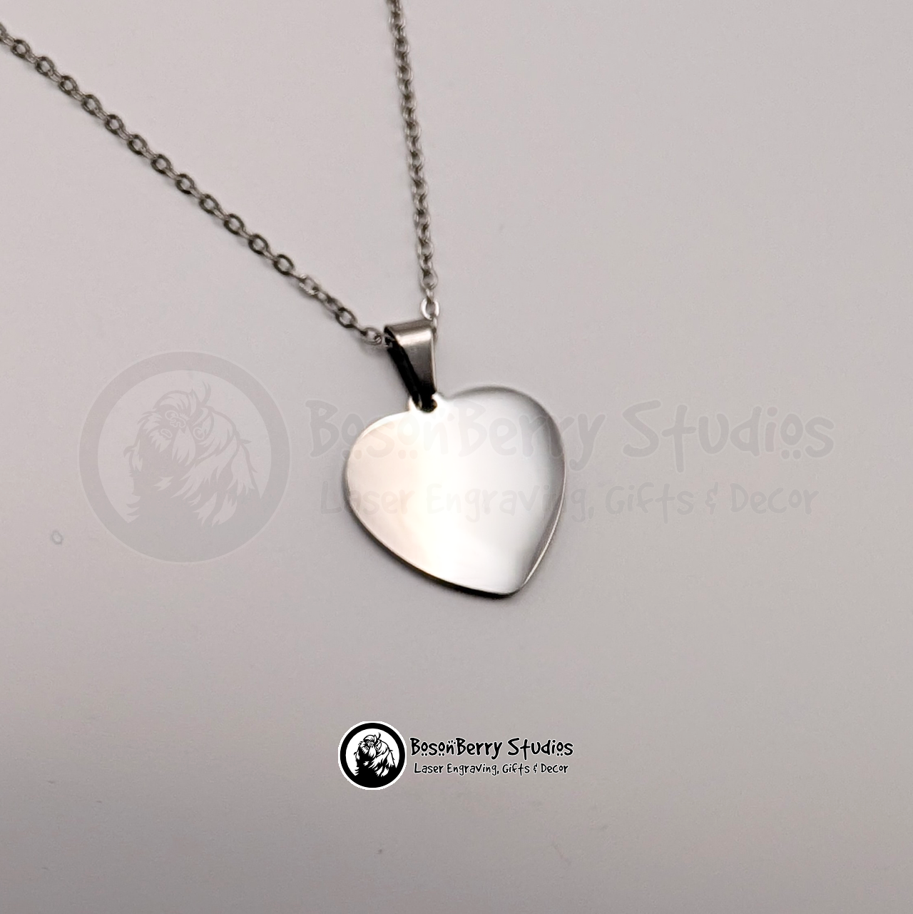 Silver heart-shaped pendant necklace on a white background with 'BosonBerry Studios' branding.
