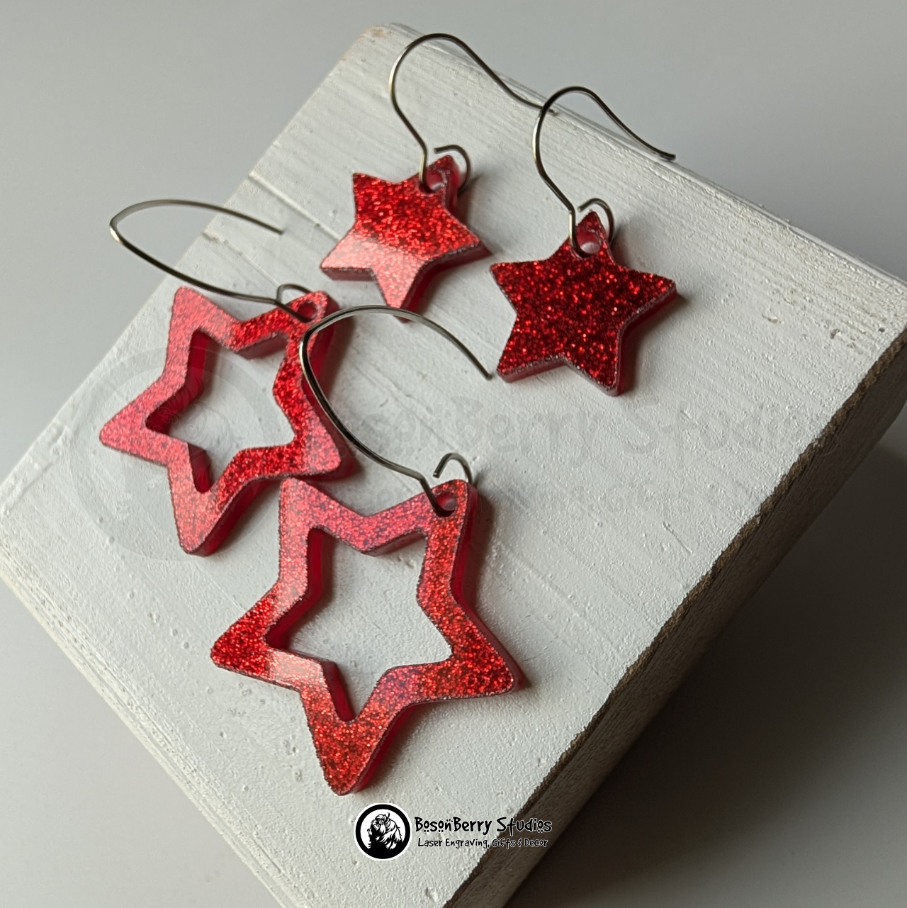 Star-shaped red glitter earrings on a white background, branded 'BosonBerry Studios'.