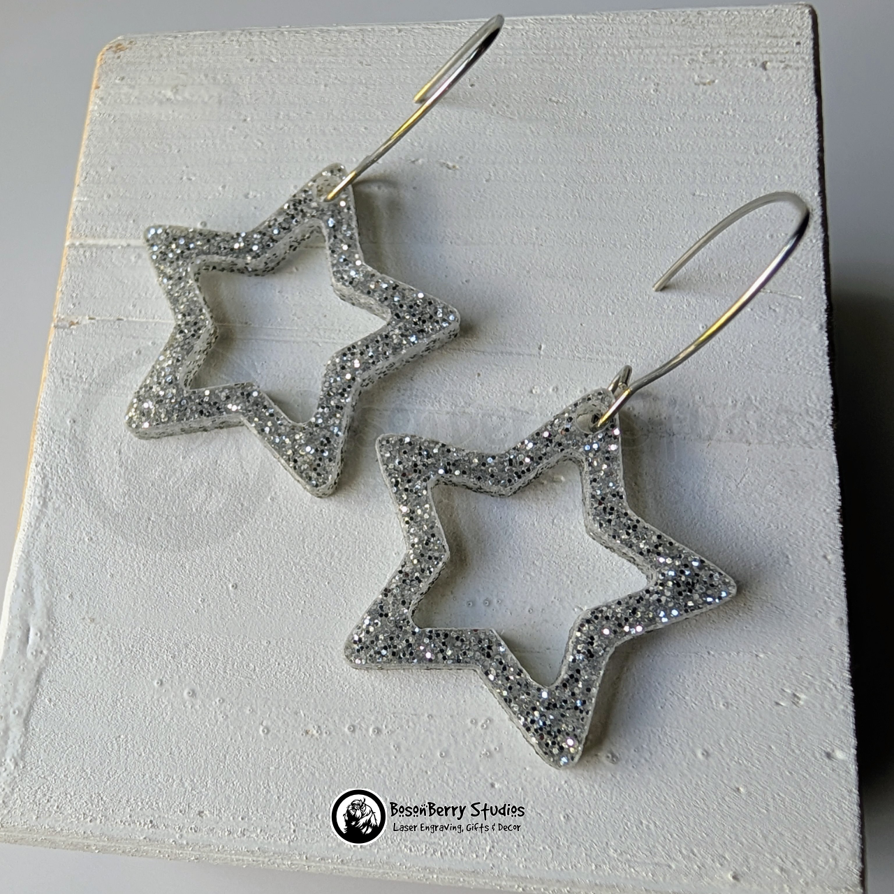 Star-shaped silver glitter earrings on a white background, branded 'BosonBerry Studios'.
