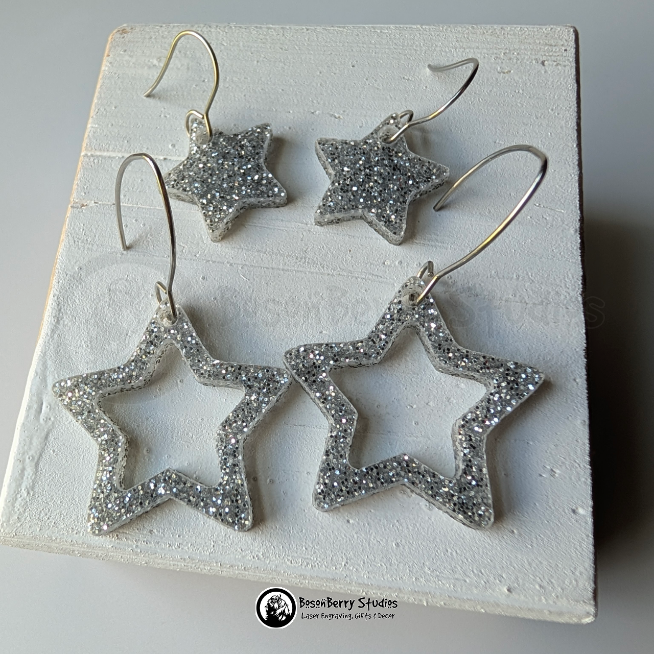 Star-shaped silver glitter earrings on a white background, branded 'BosonBerry Studios'.