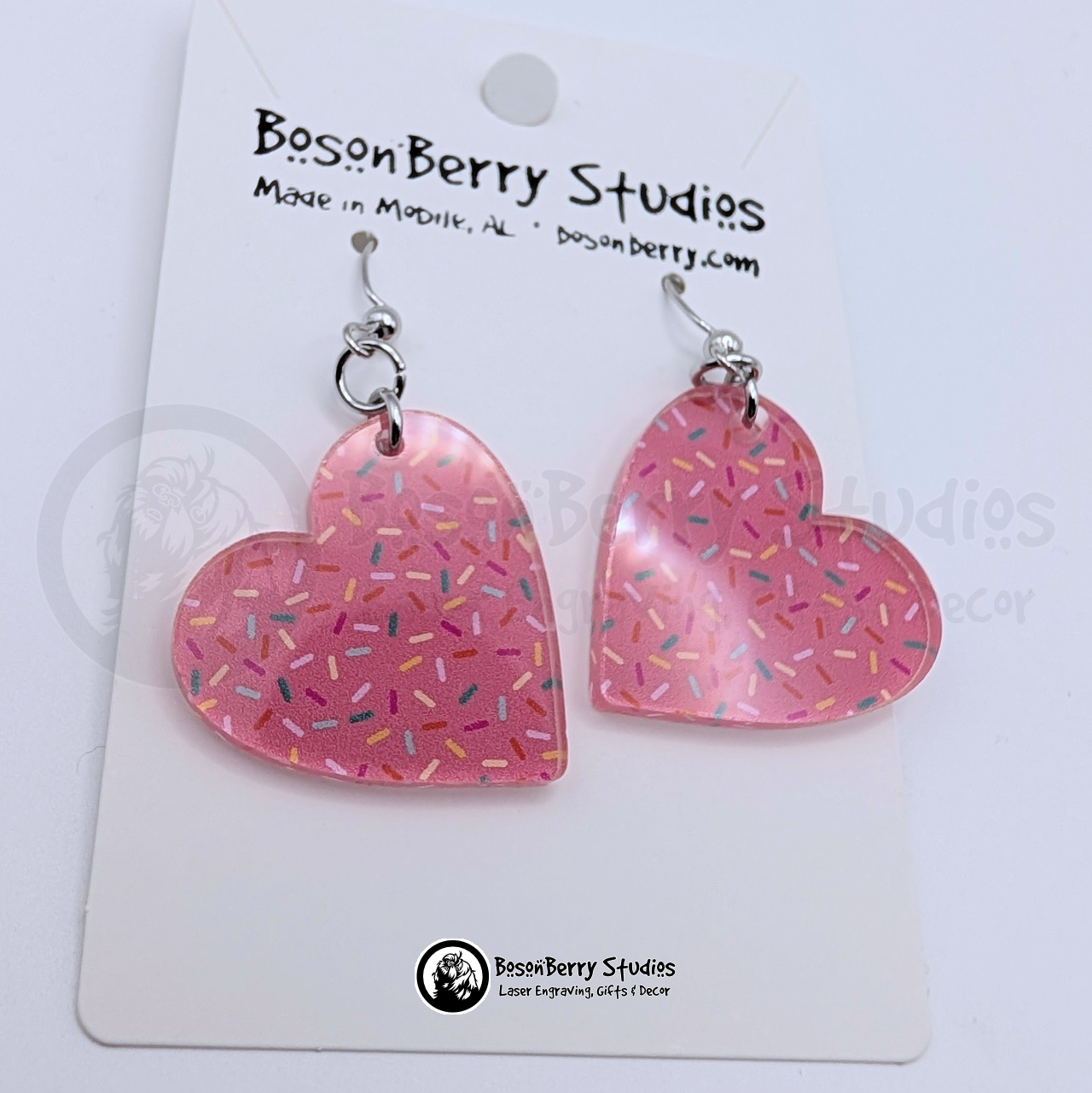 Pink heart-shaped earrings with a colorful sprinkles pattern, on cards with BosonBerry Studios branding.