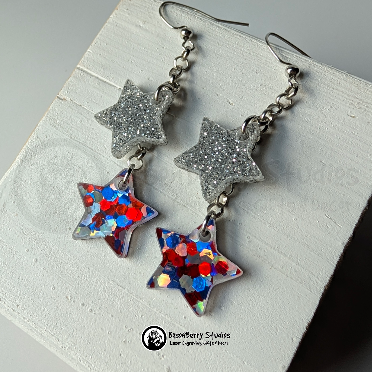 Star-shaped silver and red white blue glitter earrings on a white background, branded 'BosonBerry Studios'.
