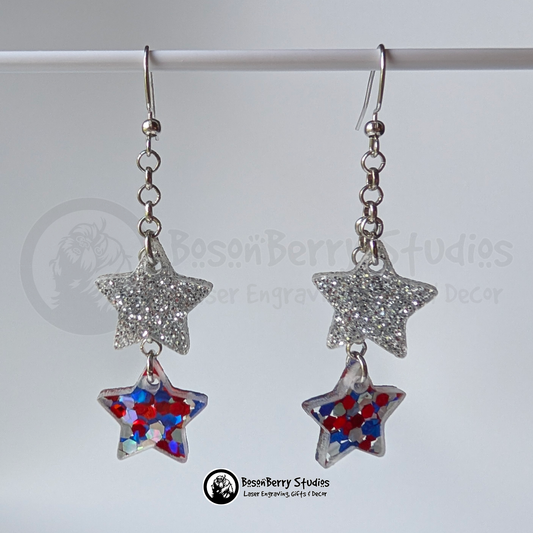 Star-shaped silver and red white blue glitter earrings suspended on a white background, branded 'BosonBerry Studios'.