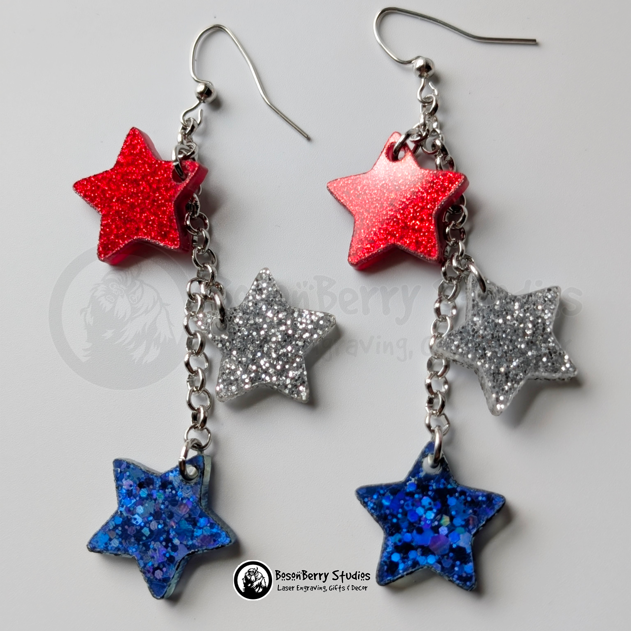 Star-shaped earrings in red, silver, and blue on a white background with "BosonBerry Studios" branding.