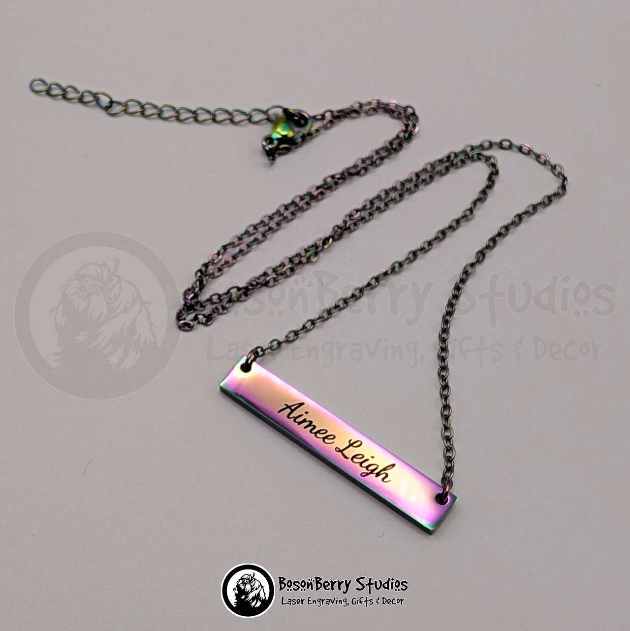Rainbow bar necklace engraved with 'Aimee Leigh' in black, cursive font, on a white background with 'BosonBerry Studios' branding.
