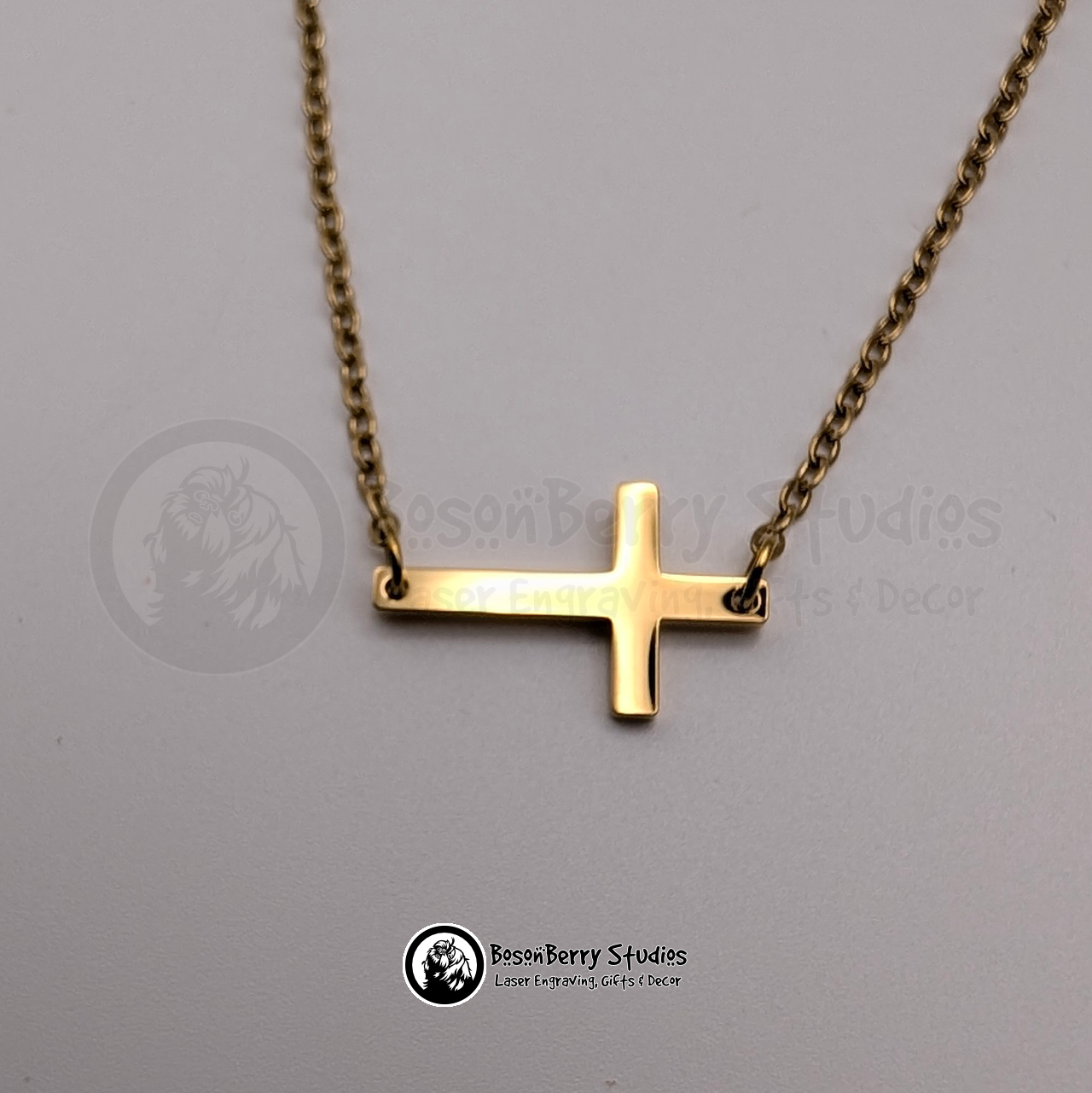 Gold tiny cross necklace on a white background with 'BosonBerry Studios' branding.