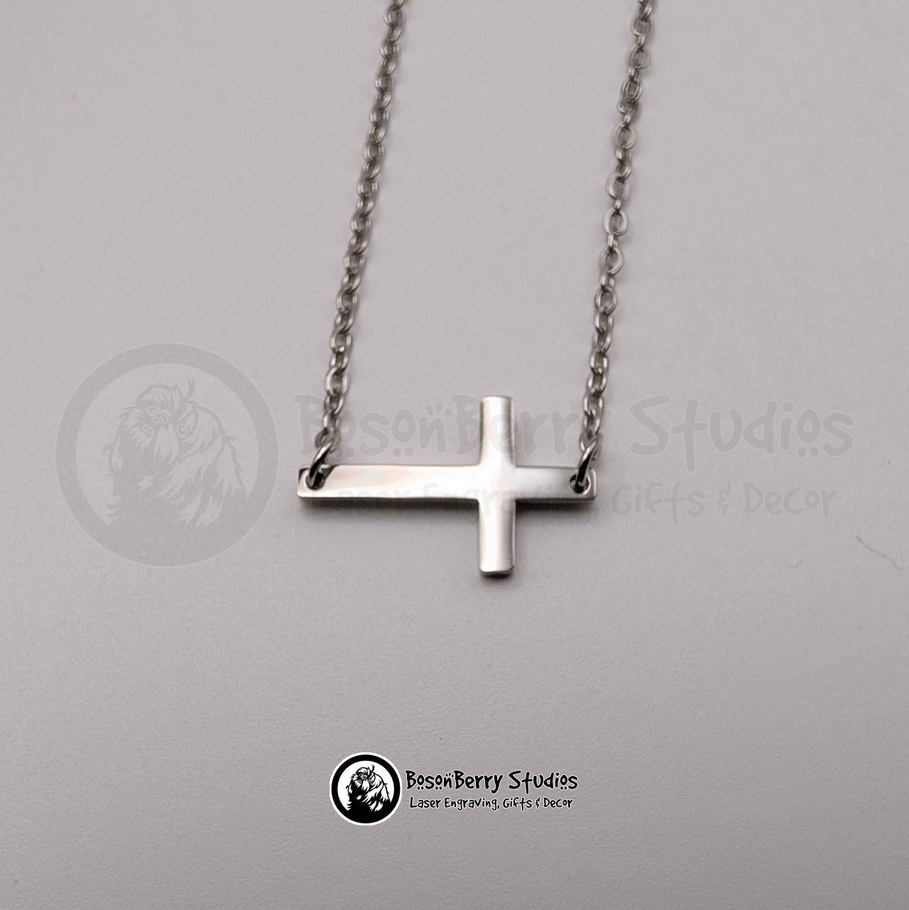 Silver tiny cross necklace on a white background with 'BosonBerry Studios' branding.
