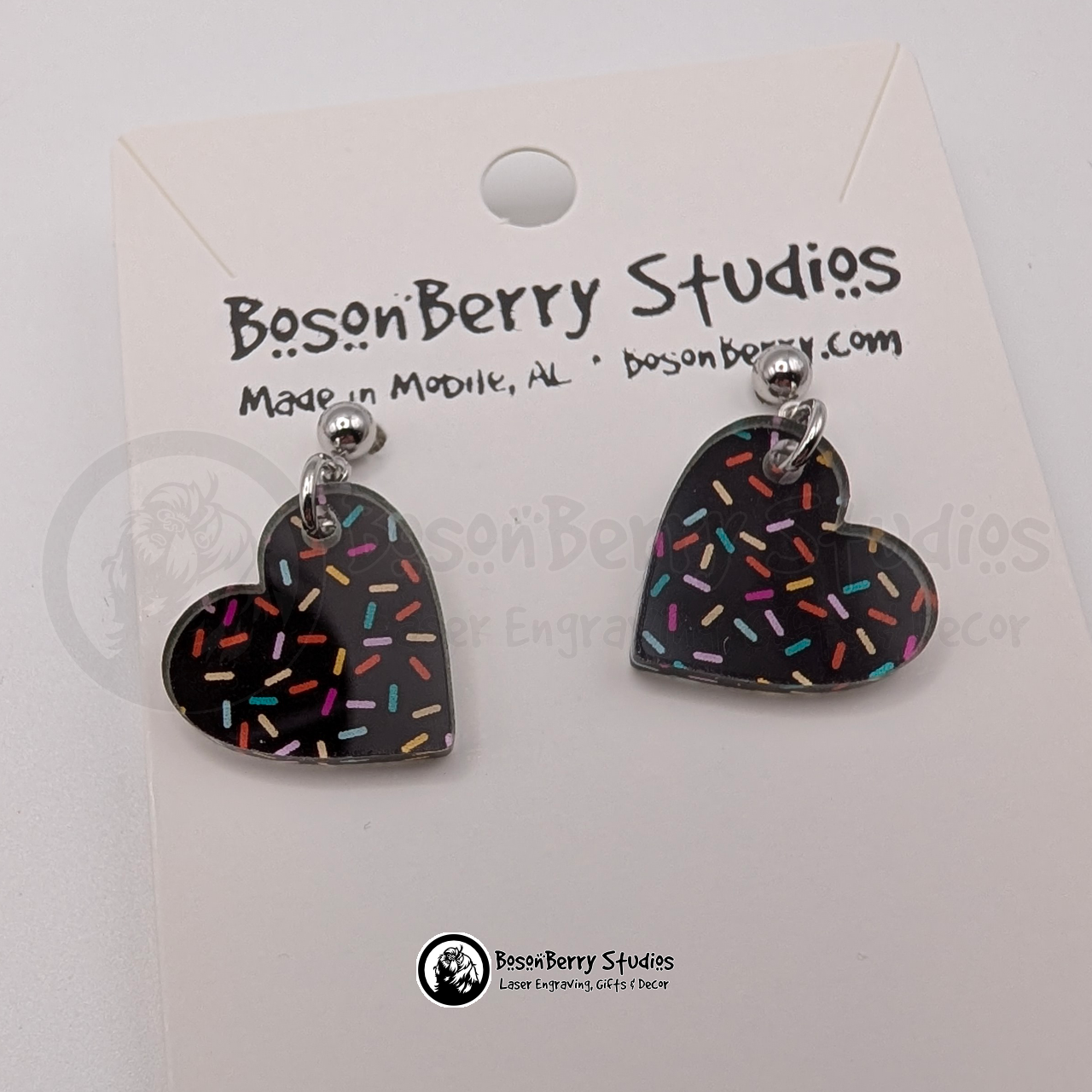 Tiny chocolate heart-shaped acrylic earrings, with a colorful sprinkle pattern, on a BosonBerry Studios card.