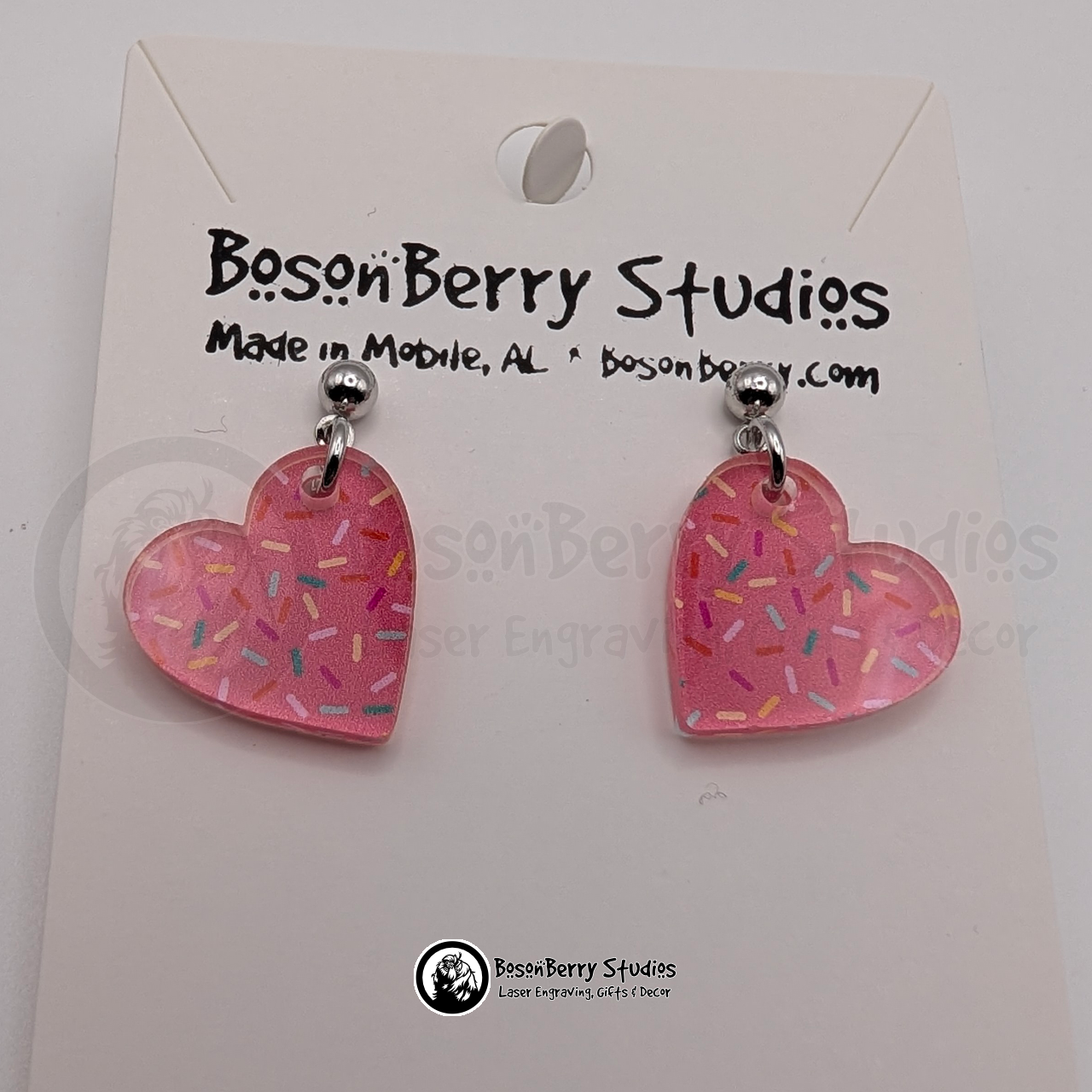 Tiny pink heart-shaped acrylic earrings, with a colorful sprinkle pattern, on a BosonBerry Studios card.