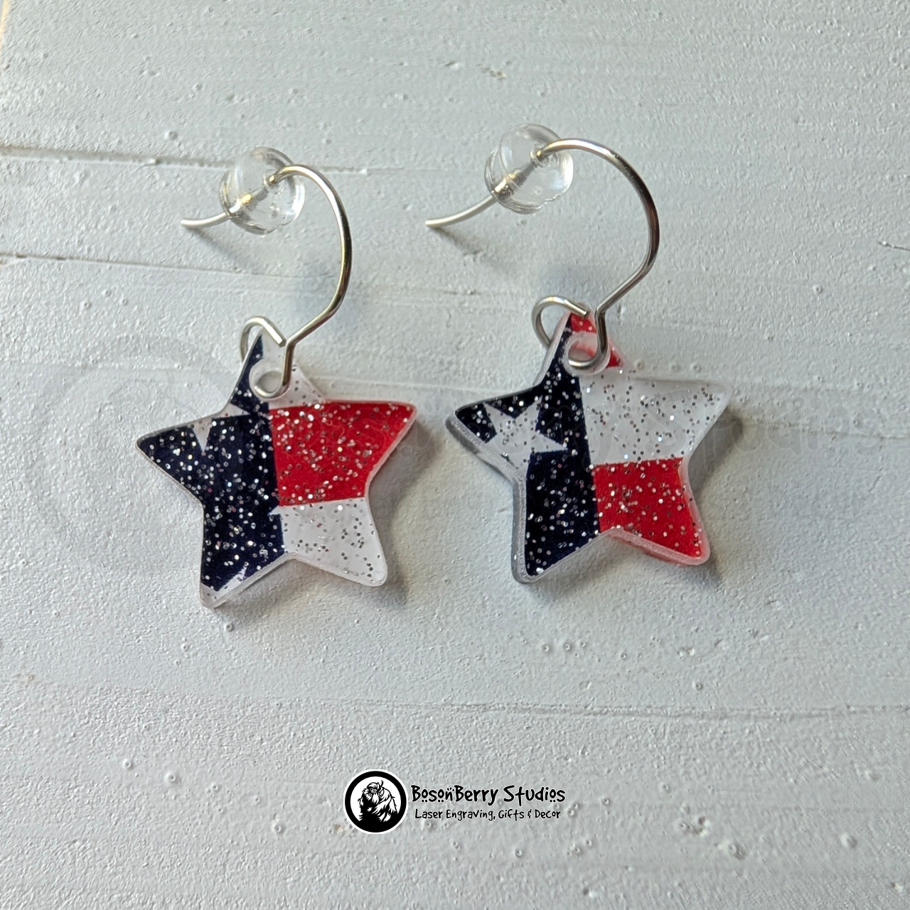 Star-shaped US Flag glitter earrings on a white background, branded 'BosonBerry Studios'.
