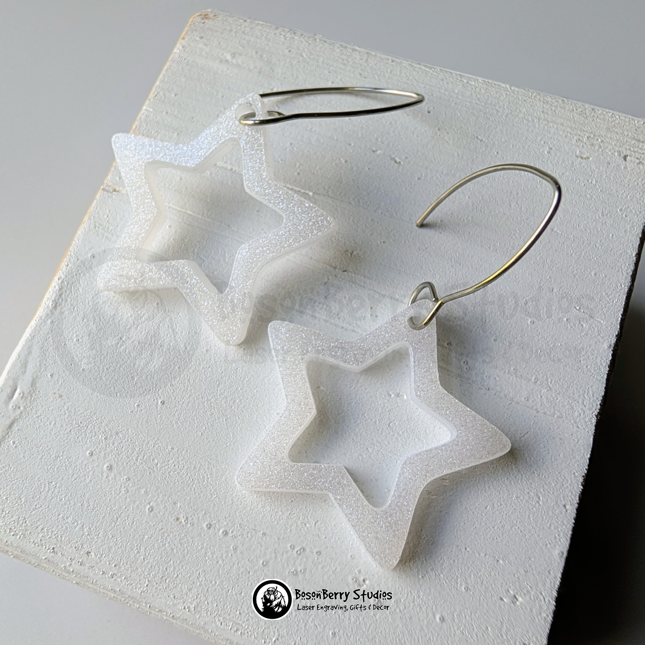 Star-shaped white glitter earrings on a white background, branded 'BosonBerry Studios'.