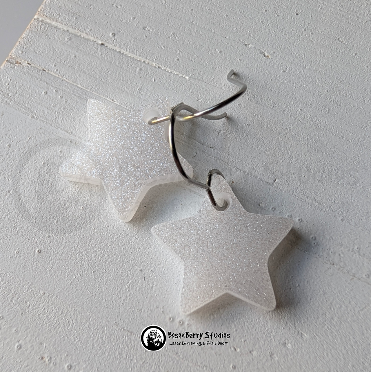 Star-shaped white glitter earrings on a white background, branded 'BosonBerry Studios'.