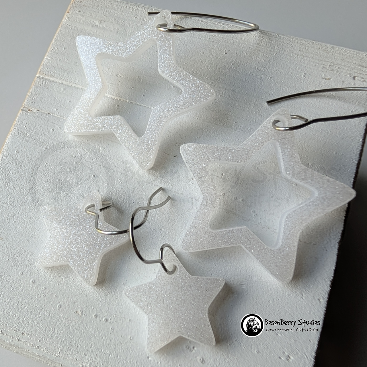 Star-shaped white glitter earrings on a white background, branded 'BosonBerry Studios'.