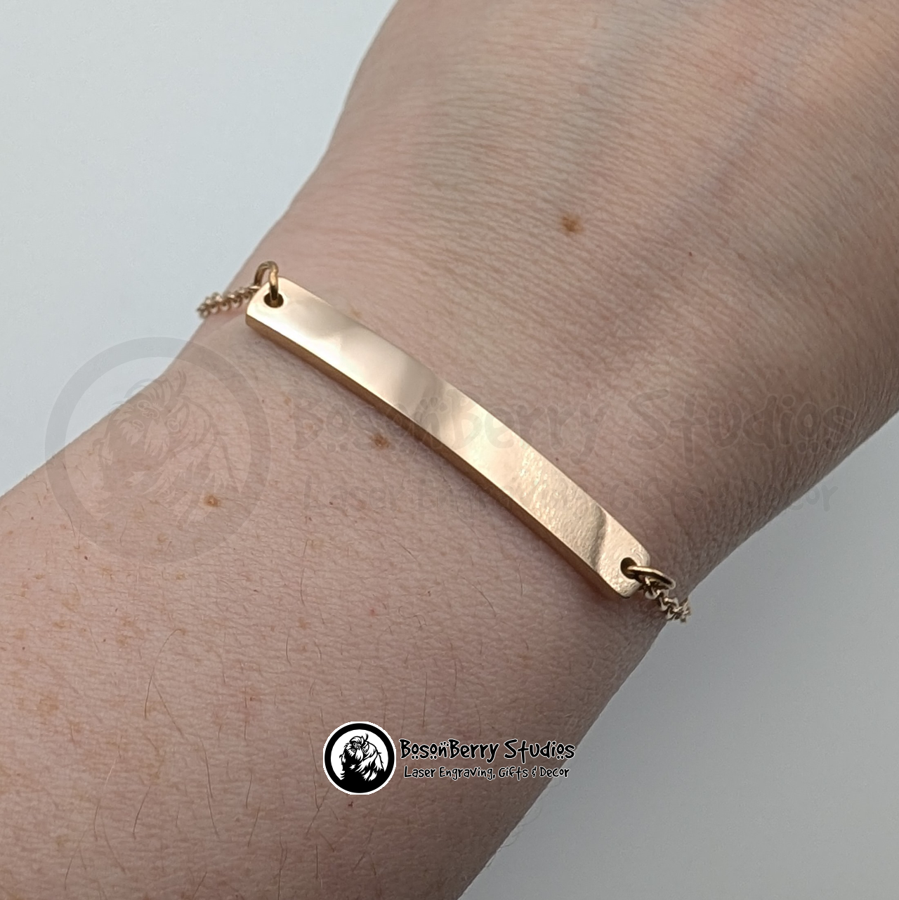 Rose gold bar bracelet on a wrist with a white background and 'BosonBerry Studios' branding.