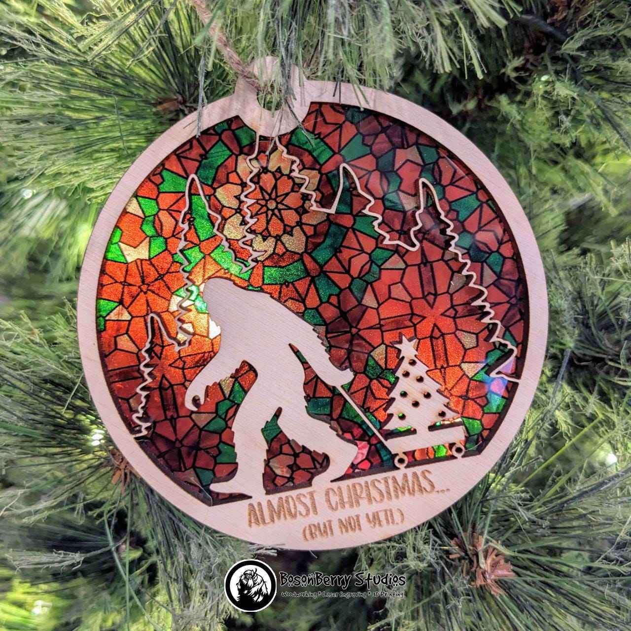 Almost Christmas (But Not Yeti) Ornament with Red Green Stained Glass transparent backer, hanging from Christmas tree